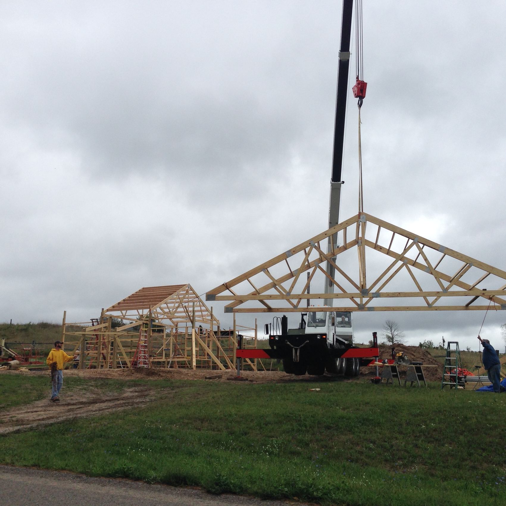 Crane lifting roof trusses on a new home build in Petoskey